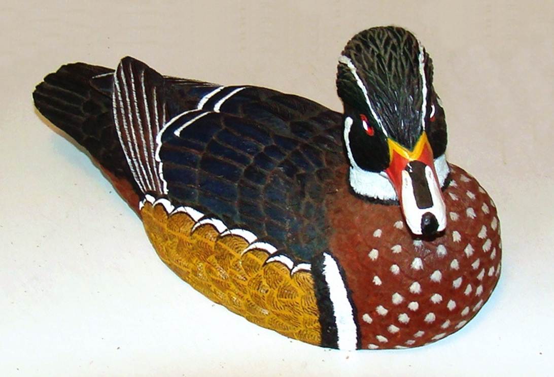 A wood duck sculpture on a white surface

AI-generated content may be incorrect.