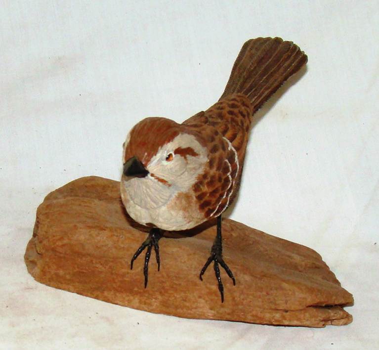 A bird statue on a piece of wood

AI-generated content may be incorrect.