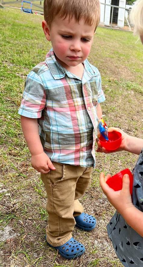 A child standing outside with a bowl of toys

Description automatically generated