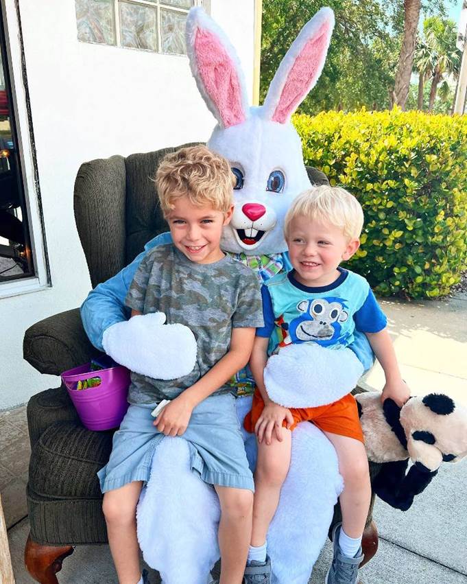 Two boys sitting on a chair with a bunny

Description automatically generated