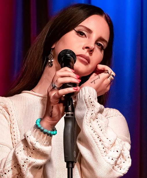 Woman holding microphone with other hand by ear with a frown.